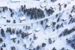 Snötäckt landskap med väg och flera hus.