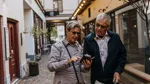Två personer som står och tittar på en telefon tillsammans.