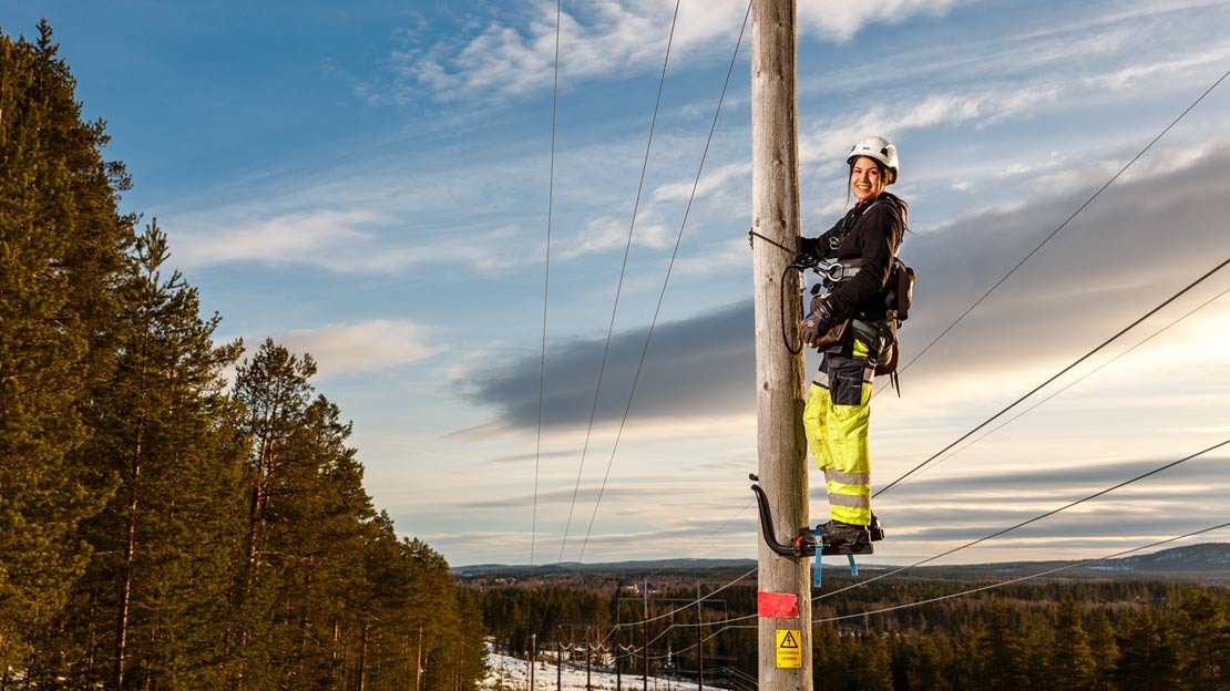 En person arbetar uppe på en kraftledningsstolpe.