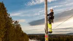En person arbetar uppe på en kraftledningsstolpe.