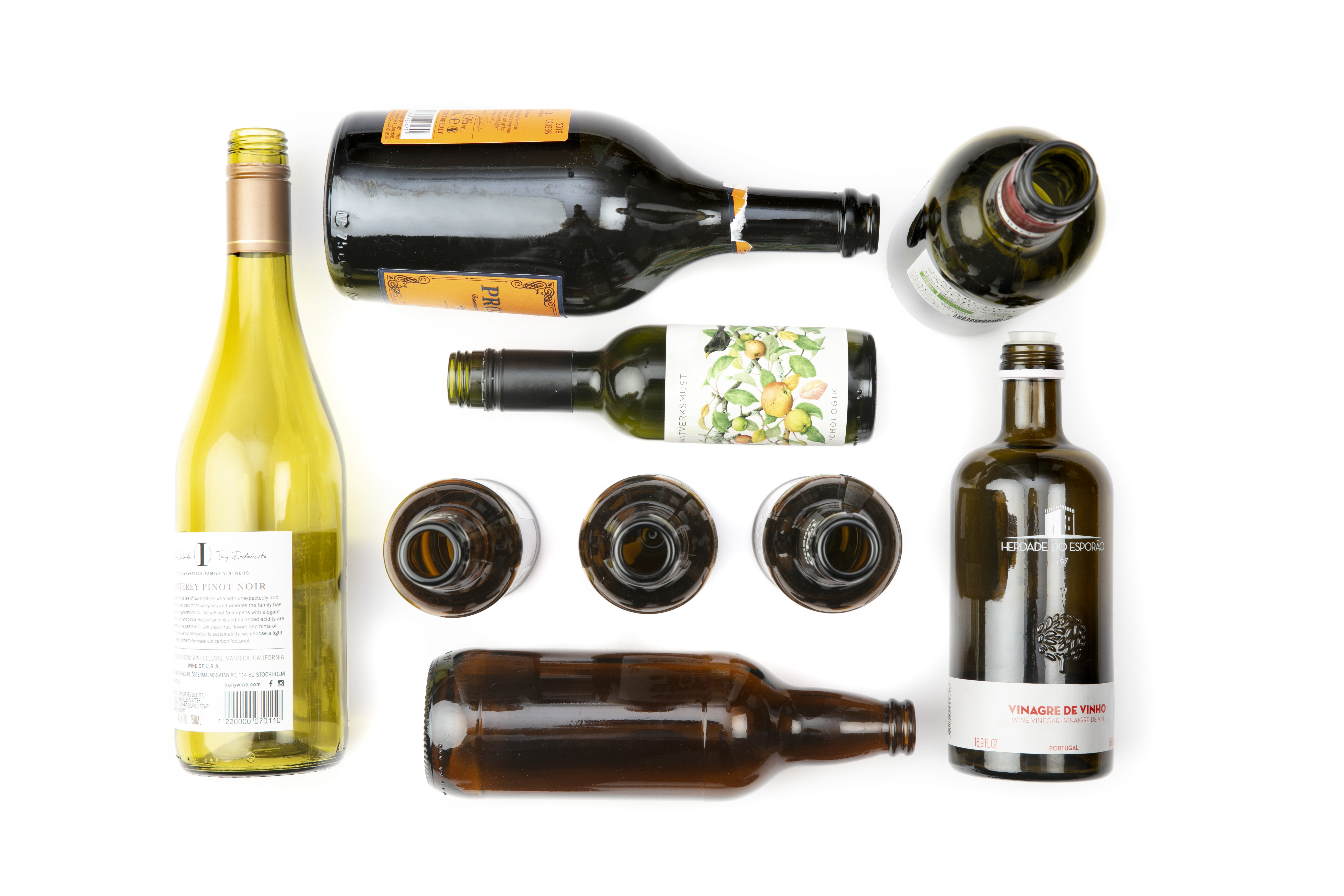 Olika tomma glasflaskor och glasburkar i varierande storlekar och färger, utlagda på vit bakgrund.