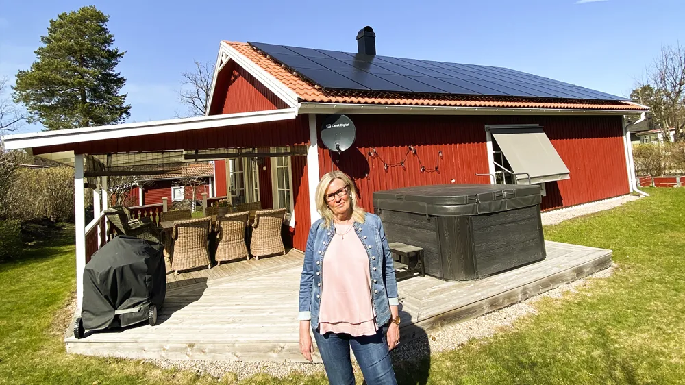 Bild på mikroproducenten Eva Eimehag som står framför sitt hus med nyinstallerade solceller på taket.