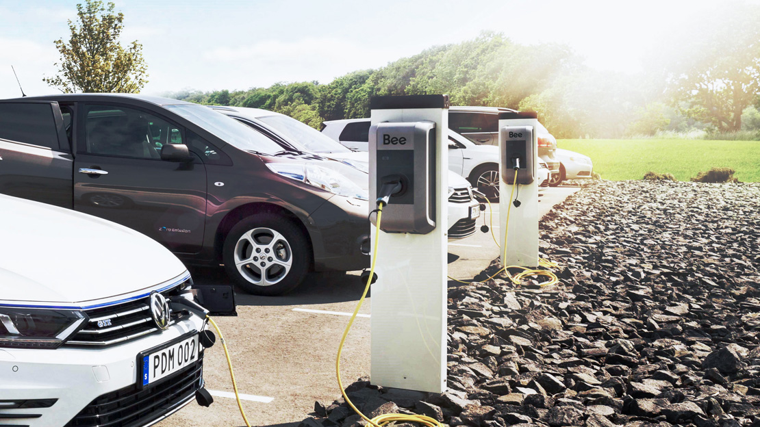 Flera elbilar som laddas vid laddboxar.