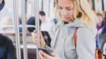 Kvinna i kollektivtrafik tittandes ner i en mobiltelefon.