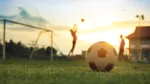 Fotboll med mål och två spelare i bakgrunden.