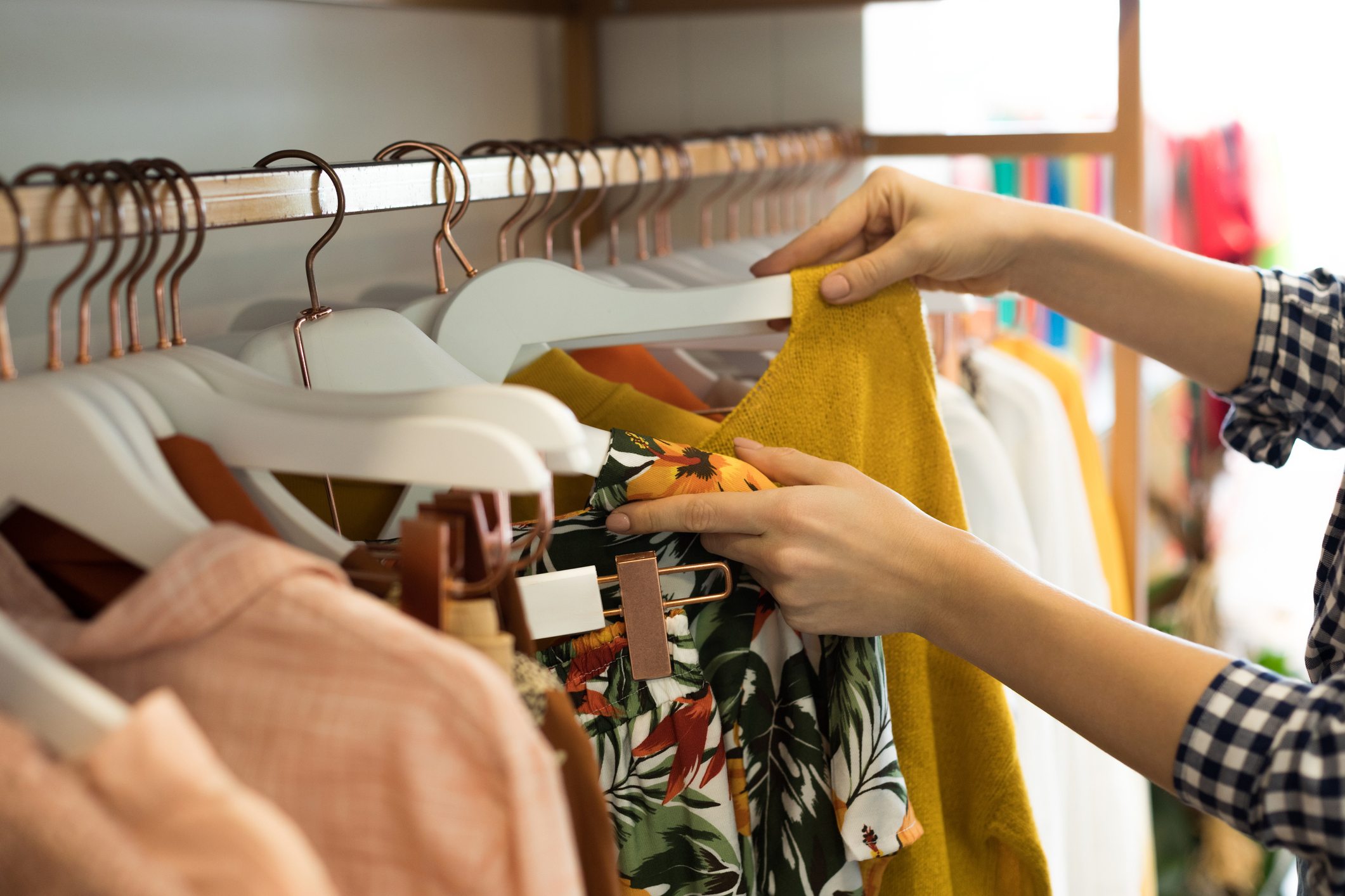 Olika kläder som hänger på galgar på en klädställning
