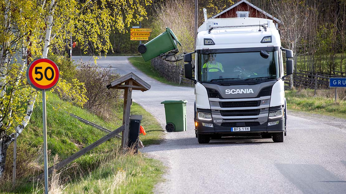 Sopbil med sidlastare tömmer ett sopkärl.