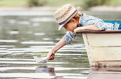 Pojke i båt lutar sig över vattnet.