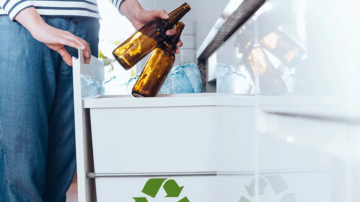 Person sopsorterar flaskor.