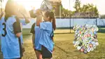 Barn iklädda fotbollströjor står på en gräsmatta och håller i en pokal