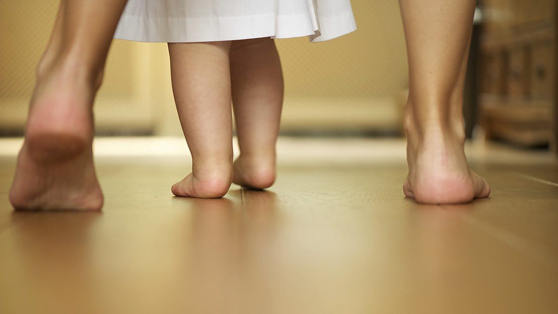 Barn- och vuxenfötter på ett golv.