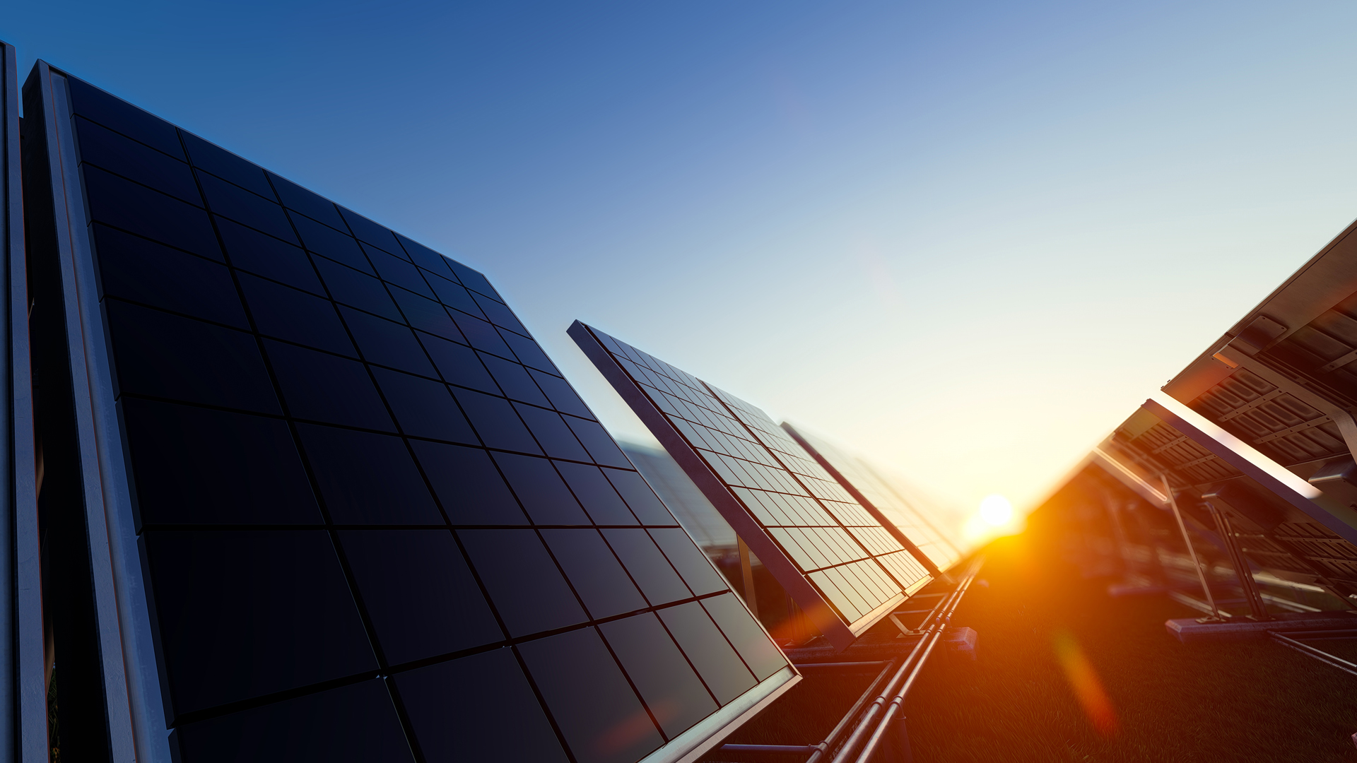 Bild på uppmonterade solceller på rad i solnedgång